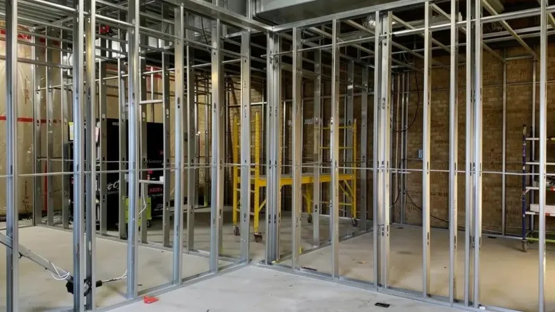 Steel stud partition walls framed inside an unfinished commercial interior, with overhead ceiling framing and ductwork