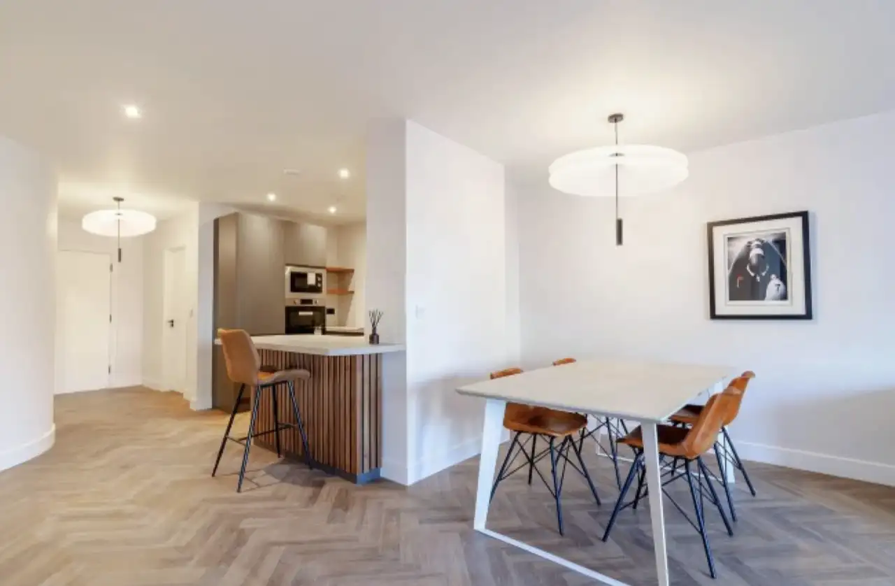 Open-plan apartment kitchen and dining area with finished painted drywall walls and ceiling, recessed lighting, and a pendant fixture
