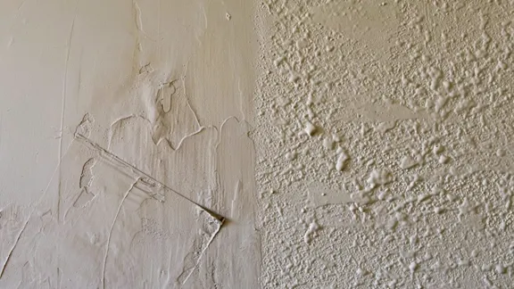 Freshly troweled joint compound on one half of a wall meeting a splatter knockdown texture on the other